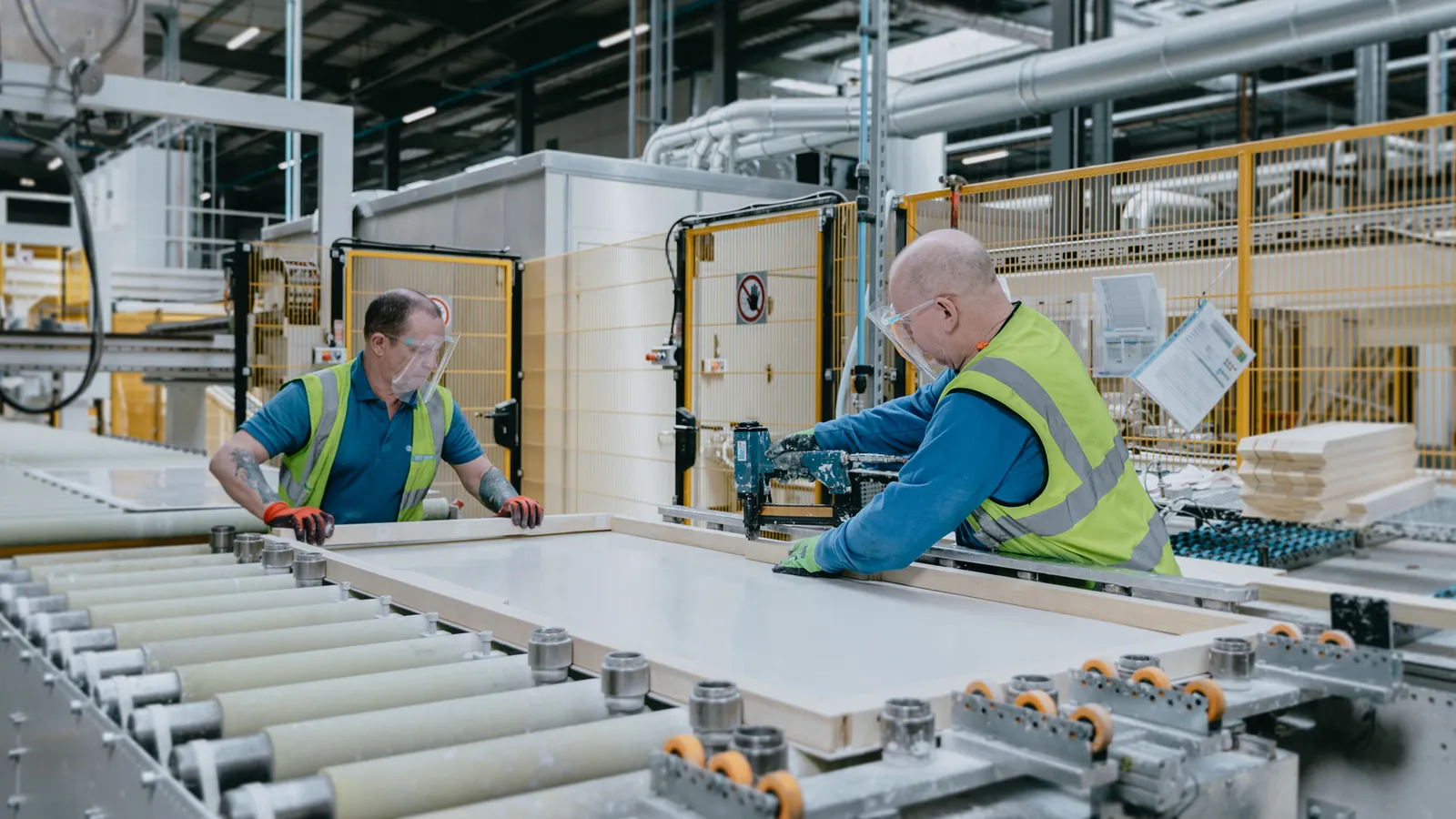 Two IG Doors operatives crafting and finishing a door slab on the factory roller line