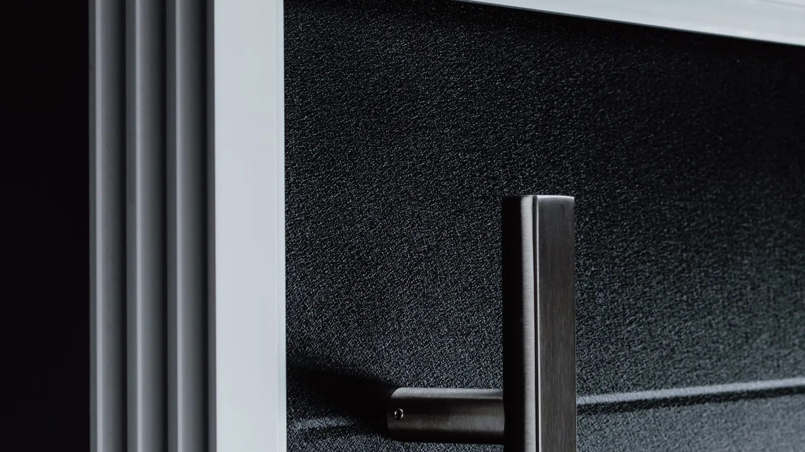 Close-up of a dark slatted Platinum44 steel door with a brushed steel bar handle