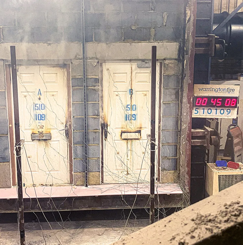 Two Ignis30 fire doors under test in a warringtonfire burn rig with the elapsed-time display running