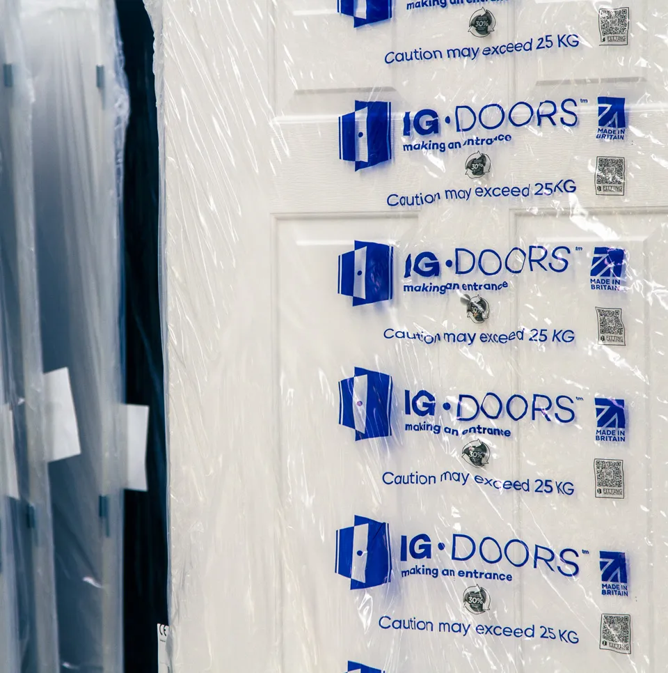 White doors shrink-wrapped in IG Doors branded protective packaging, stacked ready for delivery