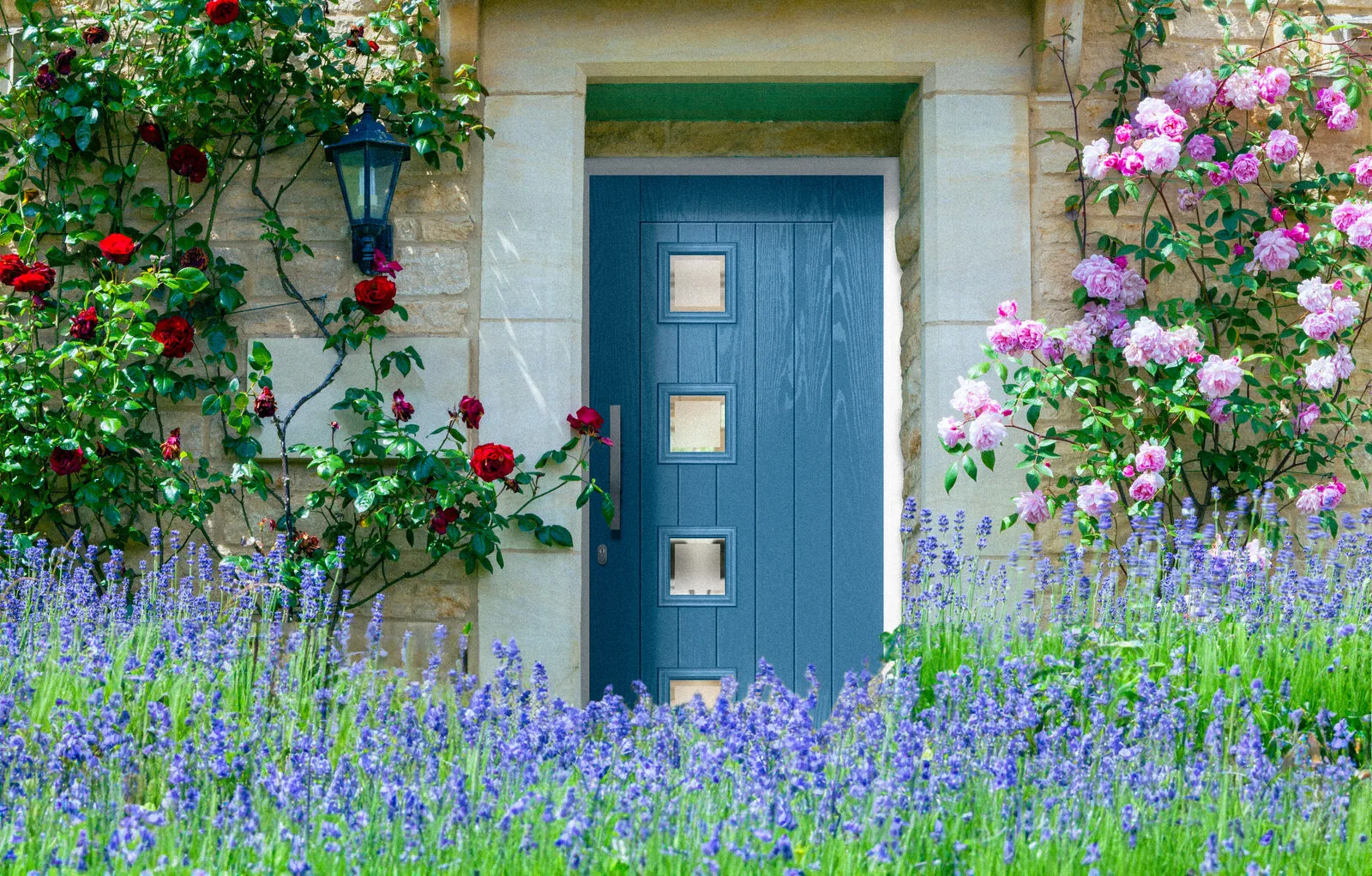 Teal composite front door in a Cotswold stone surround framed by roses
