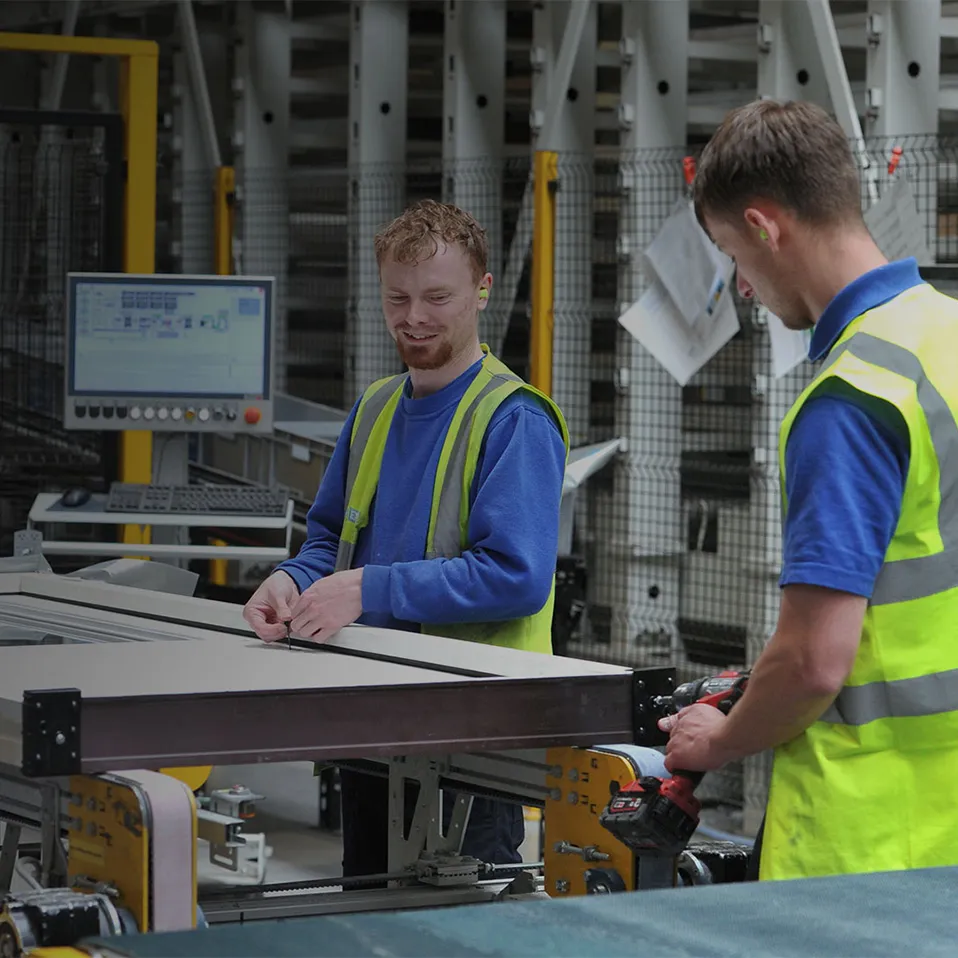 Two IG Doors production operatives in hi-vis vests assembling a door panel on the factory line
