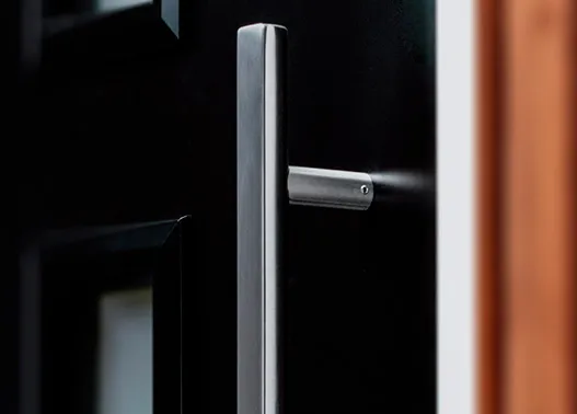 Stainless steel pull handle on a black composite front door