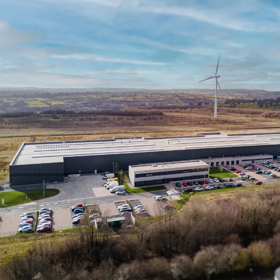 Aerial view of the IG Doors manufacturing facility in the South Wales countryside with a wind turbine behind it